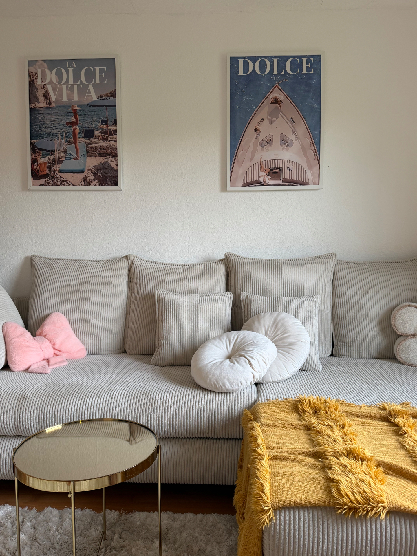 Gemütliches Wohnzimmer mit Cord-Sofa, Dolce-Vita-Postern und warmen Akzenten